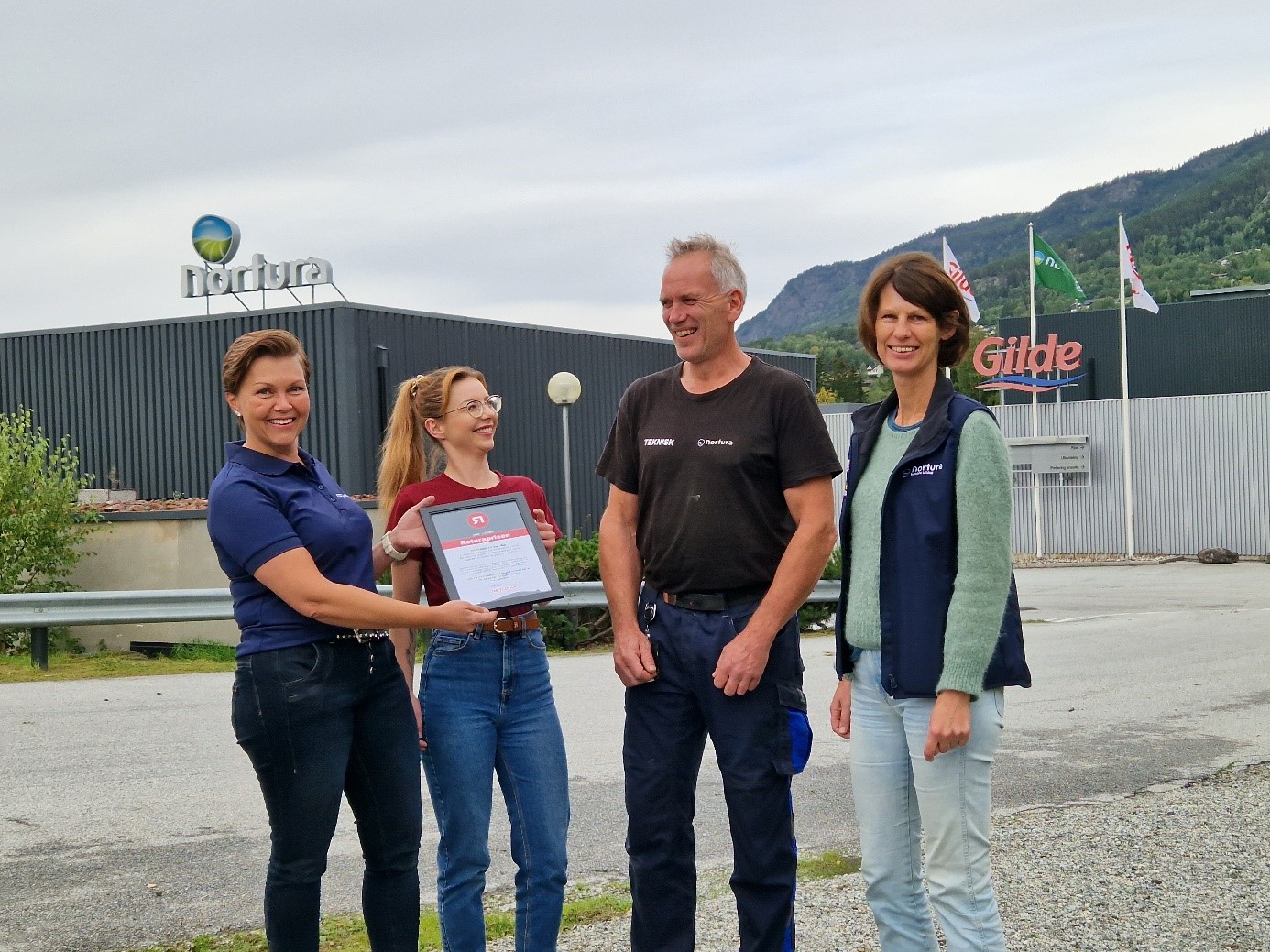Foto: Tove Sletto, markedsansvarlig i Retura Val-Hall, overrekker Returaprisen 2023 til Nortura SA avd. Gol ved Ilona Zdunek (kvalitetsleder), Henrik Brunes (teknisk sjef) og Ingrid Hillestad Medhus (fabrikksjef) foran industribedriften på Gol.